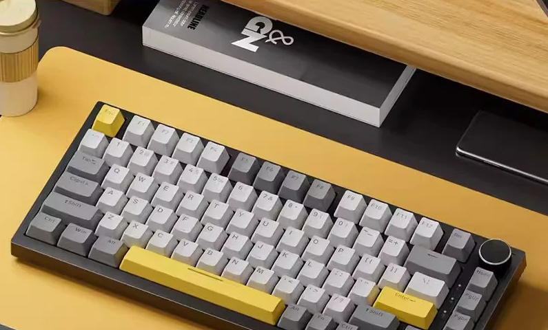 Compact 75% mechanical keyboard with grey and yellow keycaps on a bright yellow desk mat